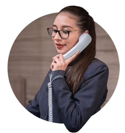 Professional woman speaking on a telephone at a reception desk.